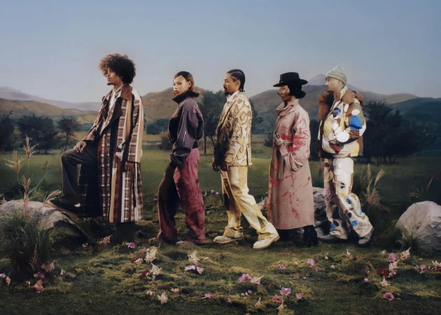 Five models in patterned and textured outerwear posing in a grassy landscape with rolling hills for KidSuper Fall 2025 campaign