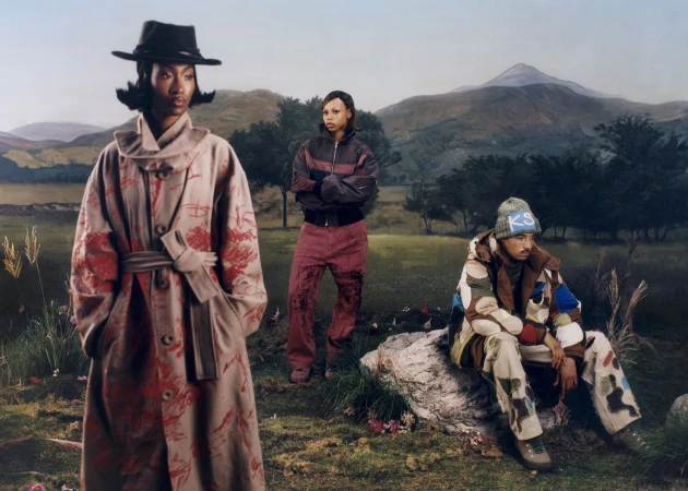 Three models wearing patterned streetwear in a scenic mountain landscape for KidSuper fall 2025 ad campaign.