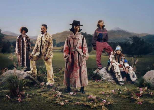 Five models in patterned streetwear pose outdoors in a rolling meadow landscape for the KidSuper Fall 2025 campaign.