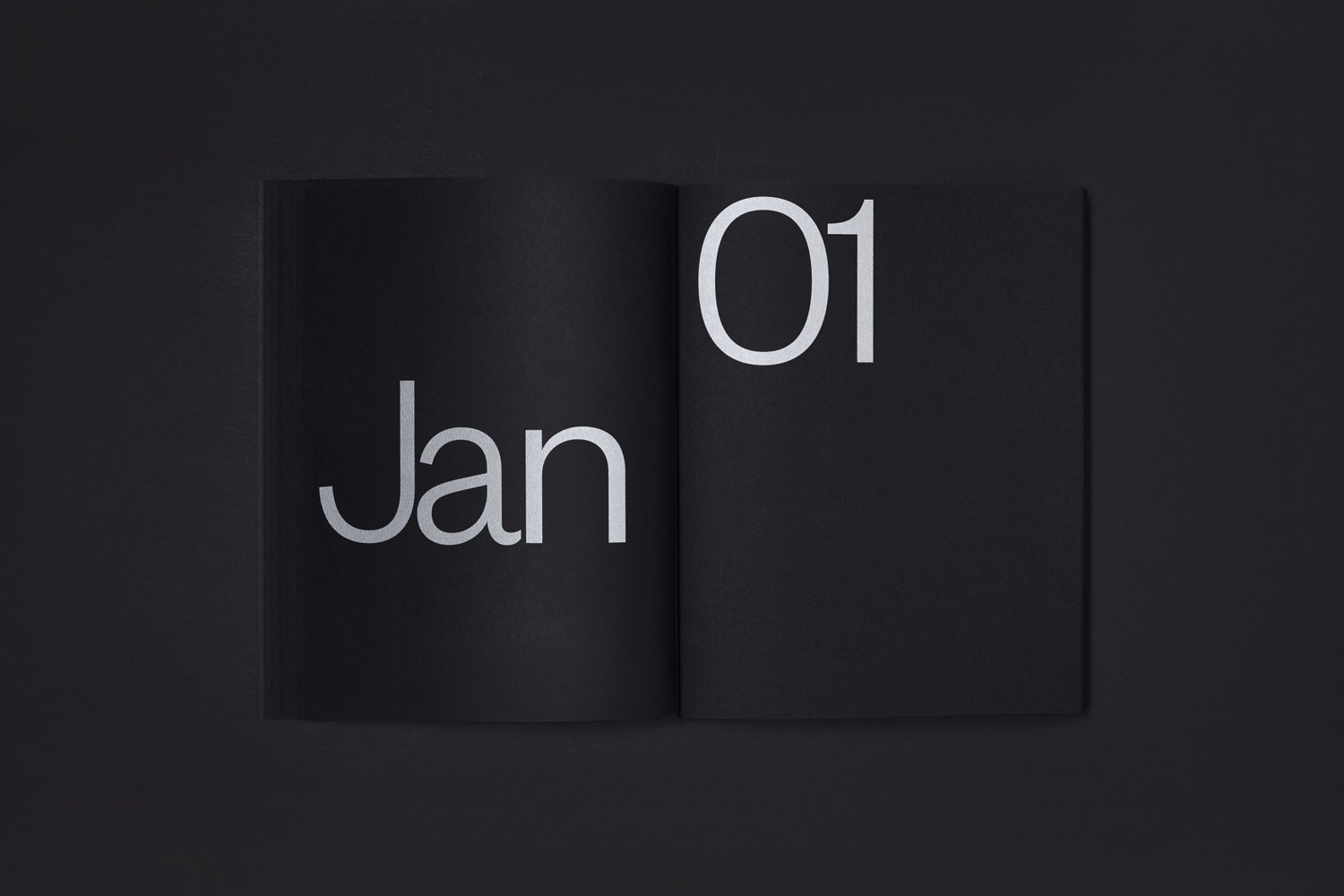 Open black book on dark surface featuring minimalist white typography with the word Jan and number 01