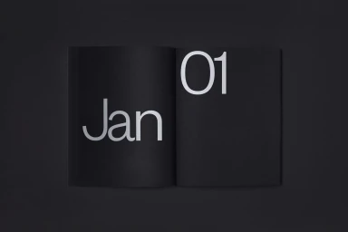 Open black book on dark surface featuring minimalist white typography with the word Jan and number 01