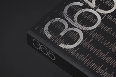 Close-up of a black bound book with metallic silver foil embossed typography and numbers reading 365 on cover and spine