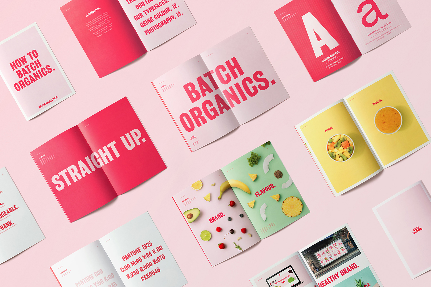 Flat lay photograph showing multiple open brand guideline booklets with pink, yellow, and green pages on a pale pink surface.