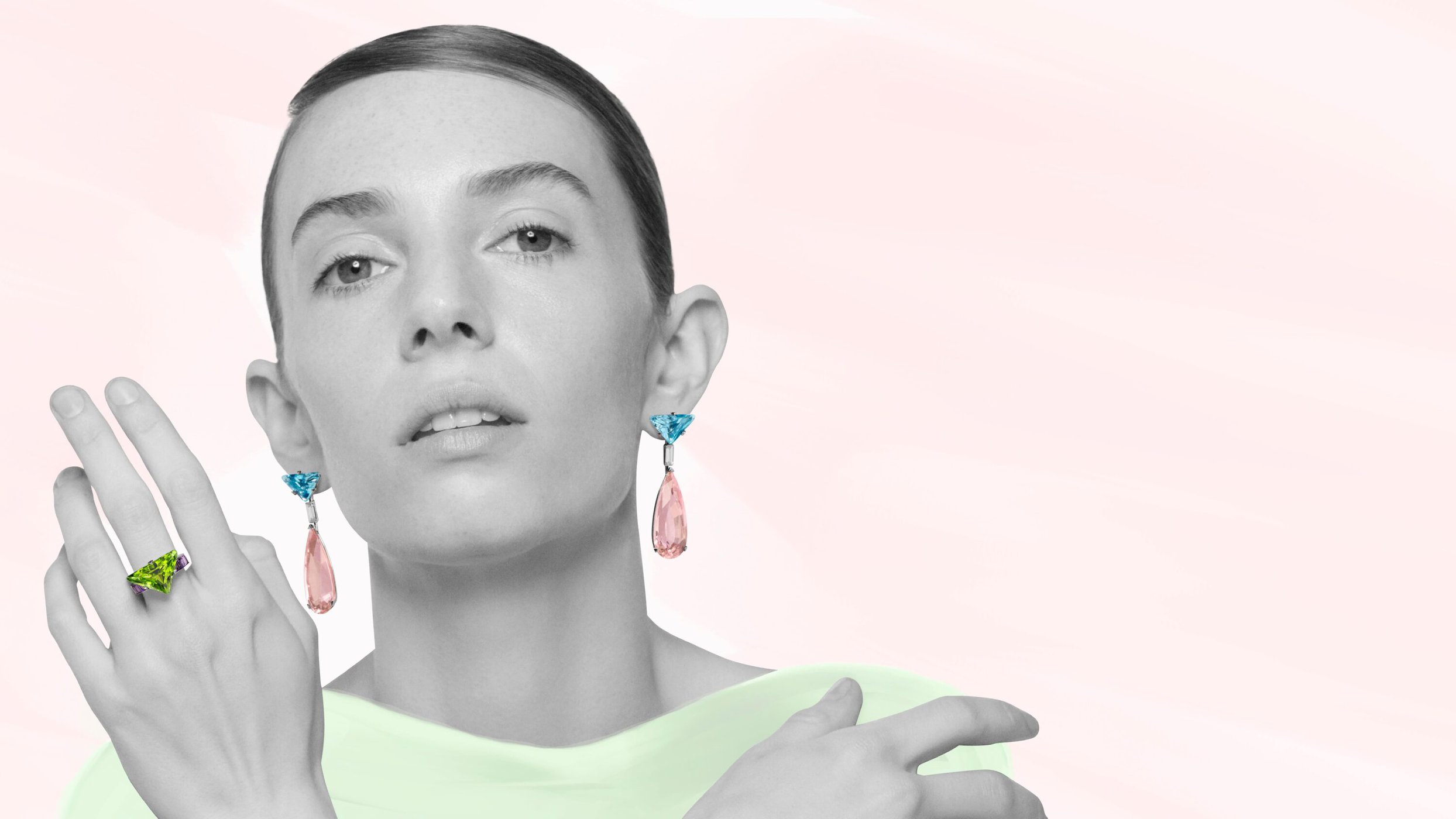 Close-up portrait of a woman wearing statement drop earrings and a large ring against a pale pink background for Prada.