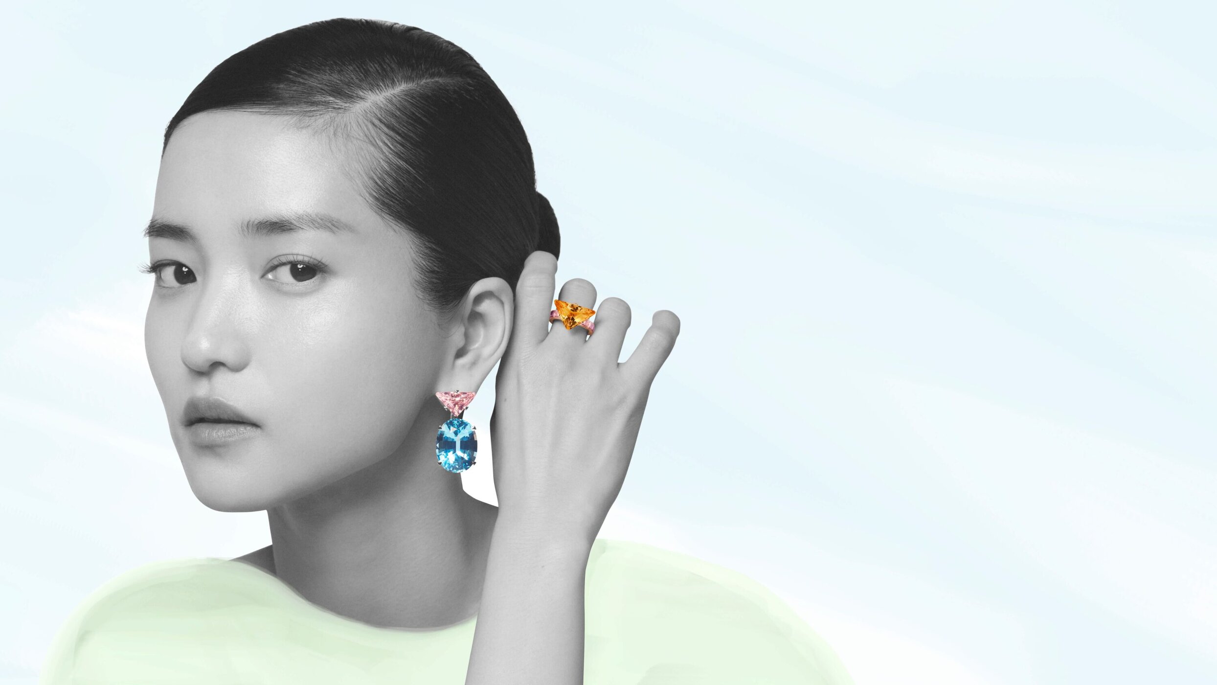 Close-up portrait of Kim Tae-Ri wearing large blue drop earrings and a prominent ring against a pale backdrop for Prada.