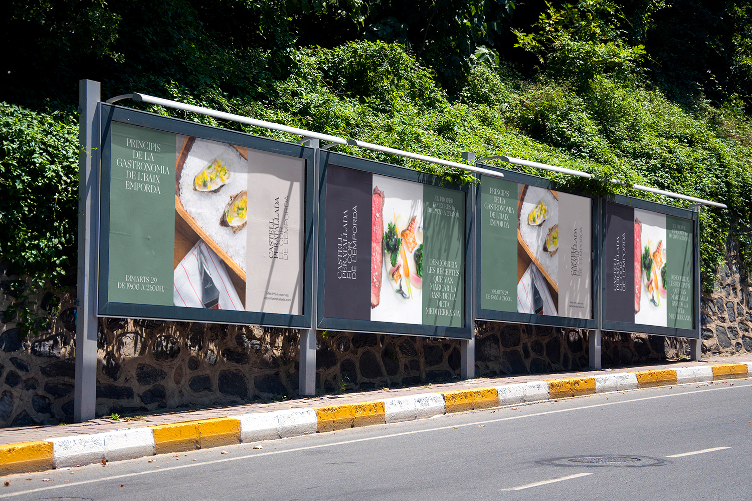 Outdoor advertising panels displaying Castell Peratallada brand identity graphics mounted along a roadside stone wall