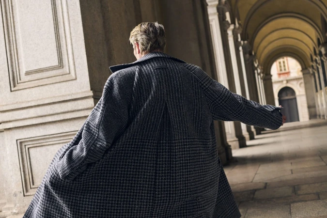 Mads Mikkelsen wearing a patterned textured coat in an arched colonnade for Zegna Fall 2025 campaign.