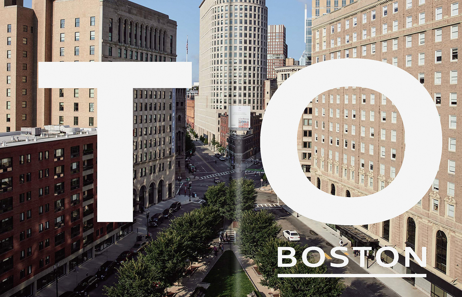 Aerial view of city streets and buildings with large bold white typography spelling out TO BOSTON across the frame