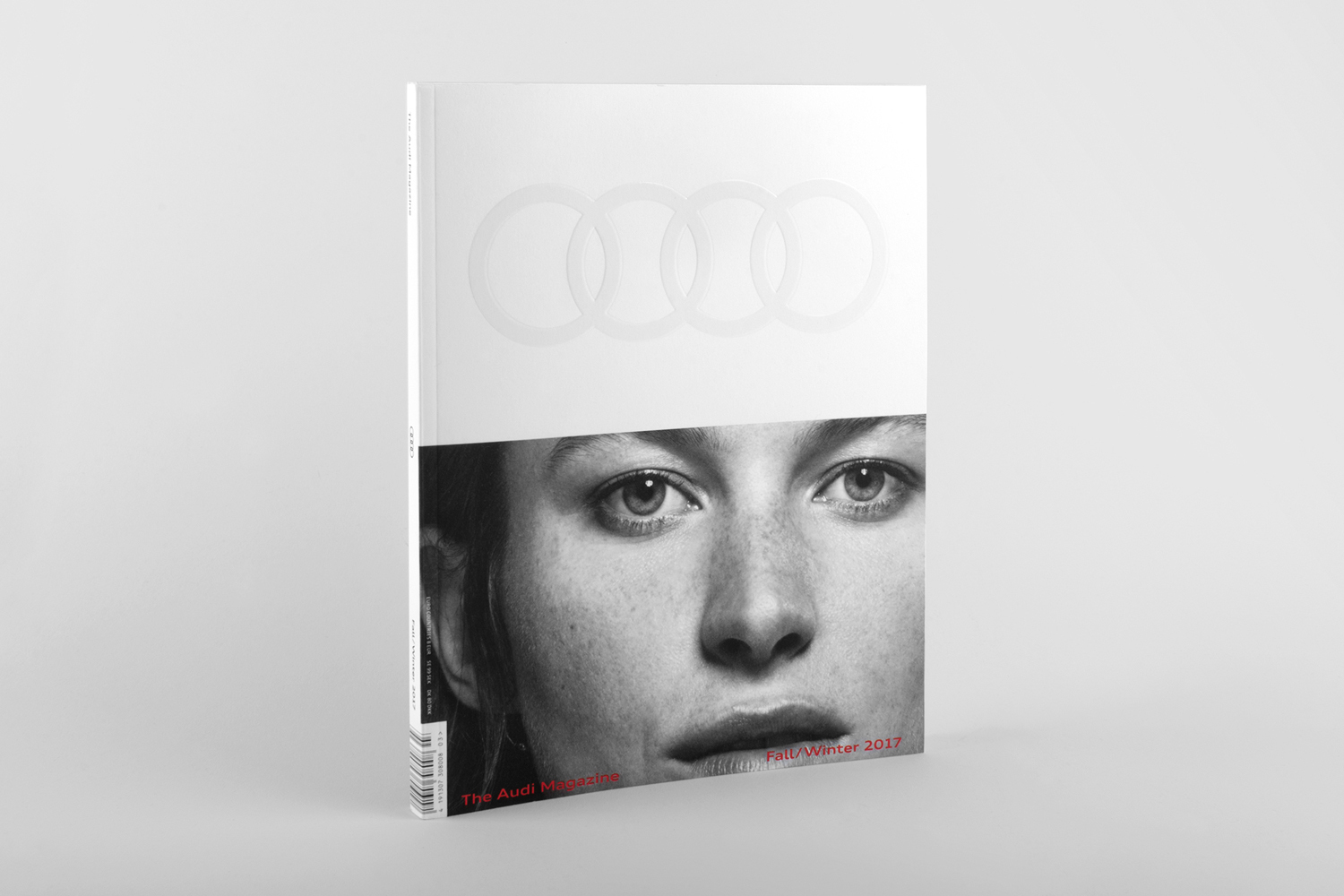 A close-up portrait of a woman's face on a magazine cover featuring the Audi brand identity and four rings logo.
