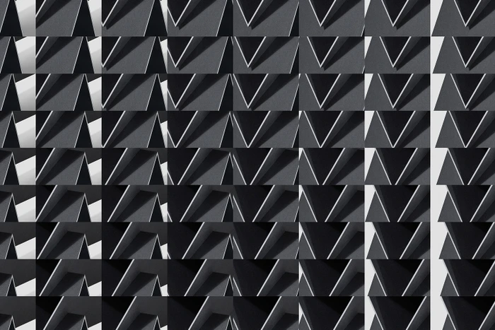 Monochrome geometric pattern featuring repeating triangular shapes and stark shadows creating a graphic architectural grid.