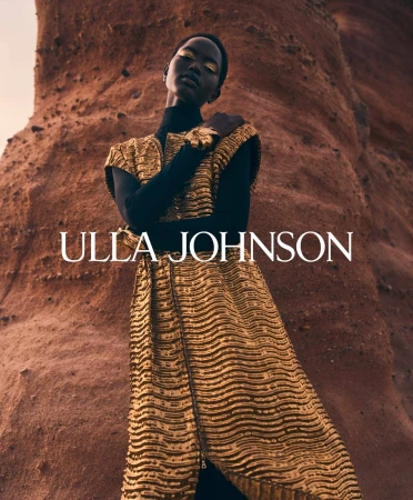 Model in a gold textured dress standing against a rocky textured background with overlaid white brand text
