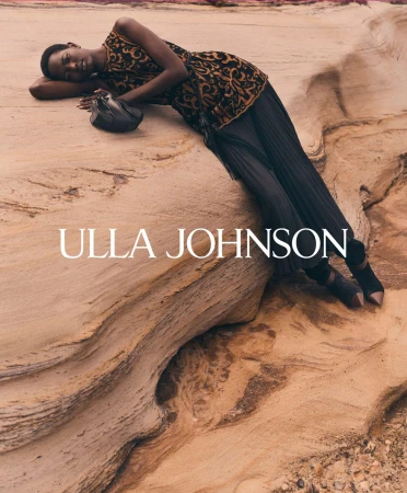 Model reclining on weathered rock formation wearing patterned top and pleated skirt for Ulla Johnson campaign