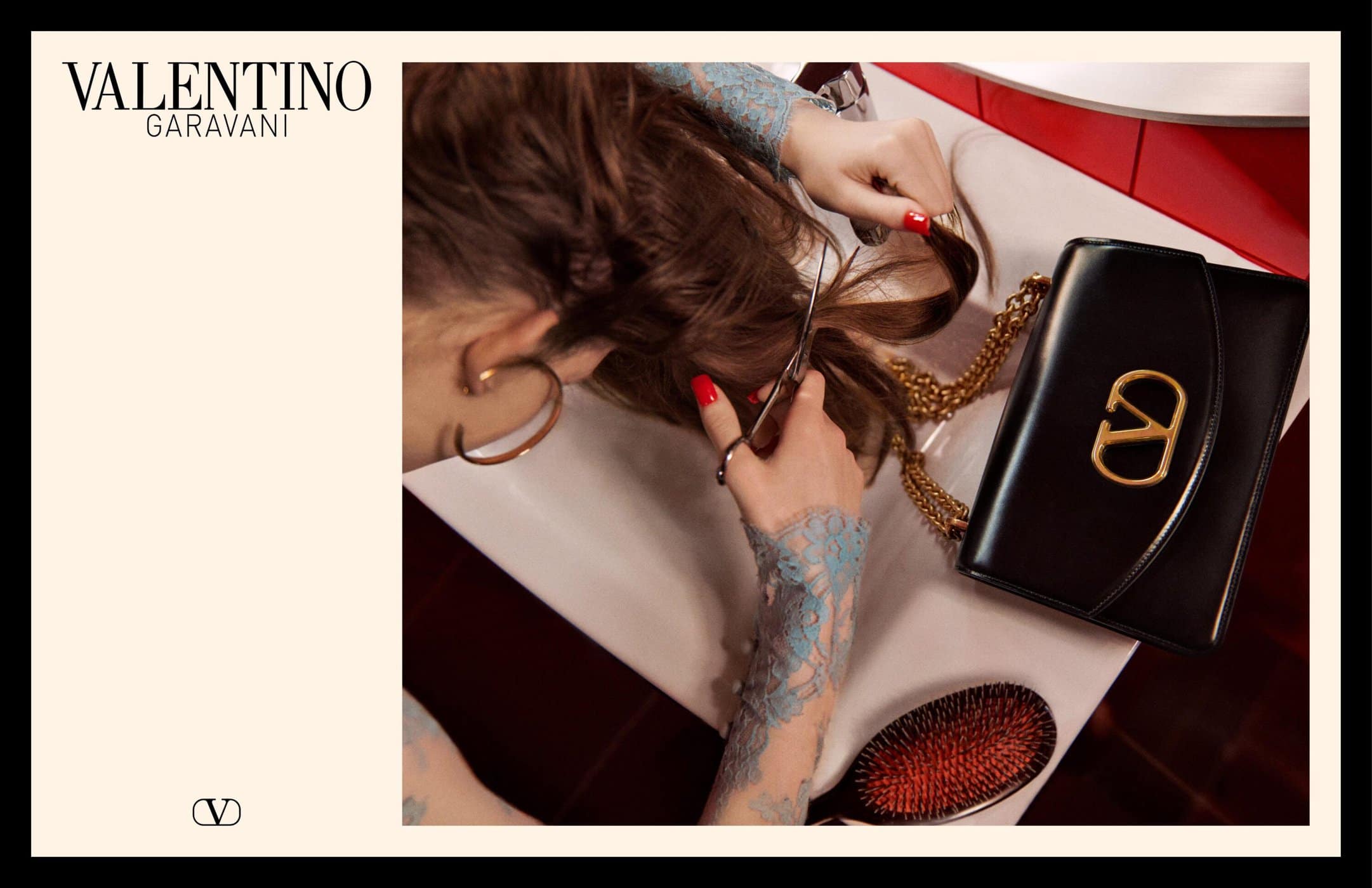 Overhead view of a person cutting hair over a white basin next to a black handbag with gold hardware