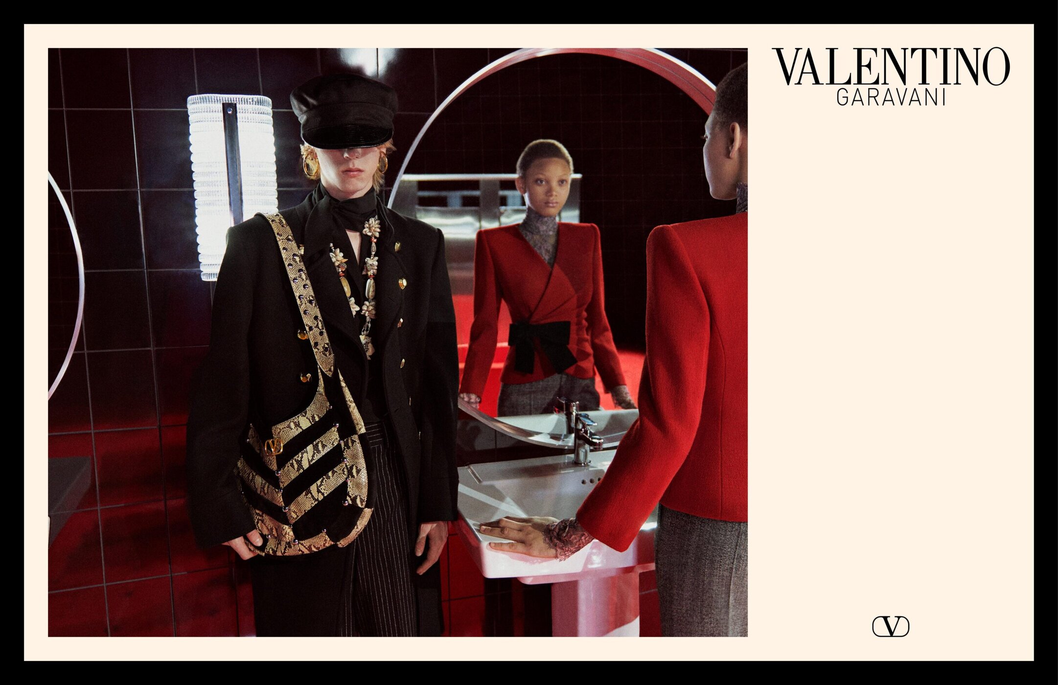 Models in a tiled restroom setting wearing tailored black and red Valentino jackets with accessories.