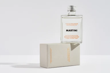 A clear glass bottled martini resting on top of a light grey box against a seamless white background for The Everleigh brand identity.