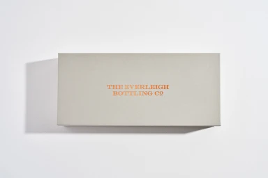 Rectangular grey rigid box with metallic copper foil lettering against a white seamless background