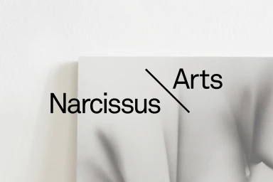 Minimalist graphic design brand identity for Narcissus Arts showing bold typography against a white wall.
