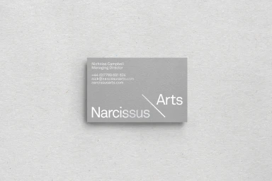 Grey business card with clean white typography resting on a textured light grey paper background