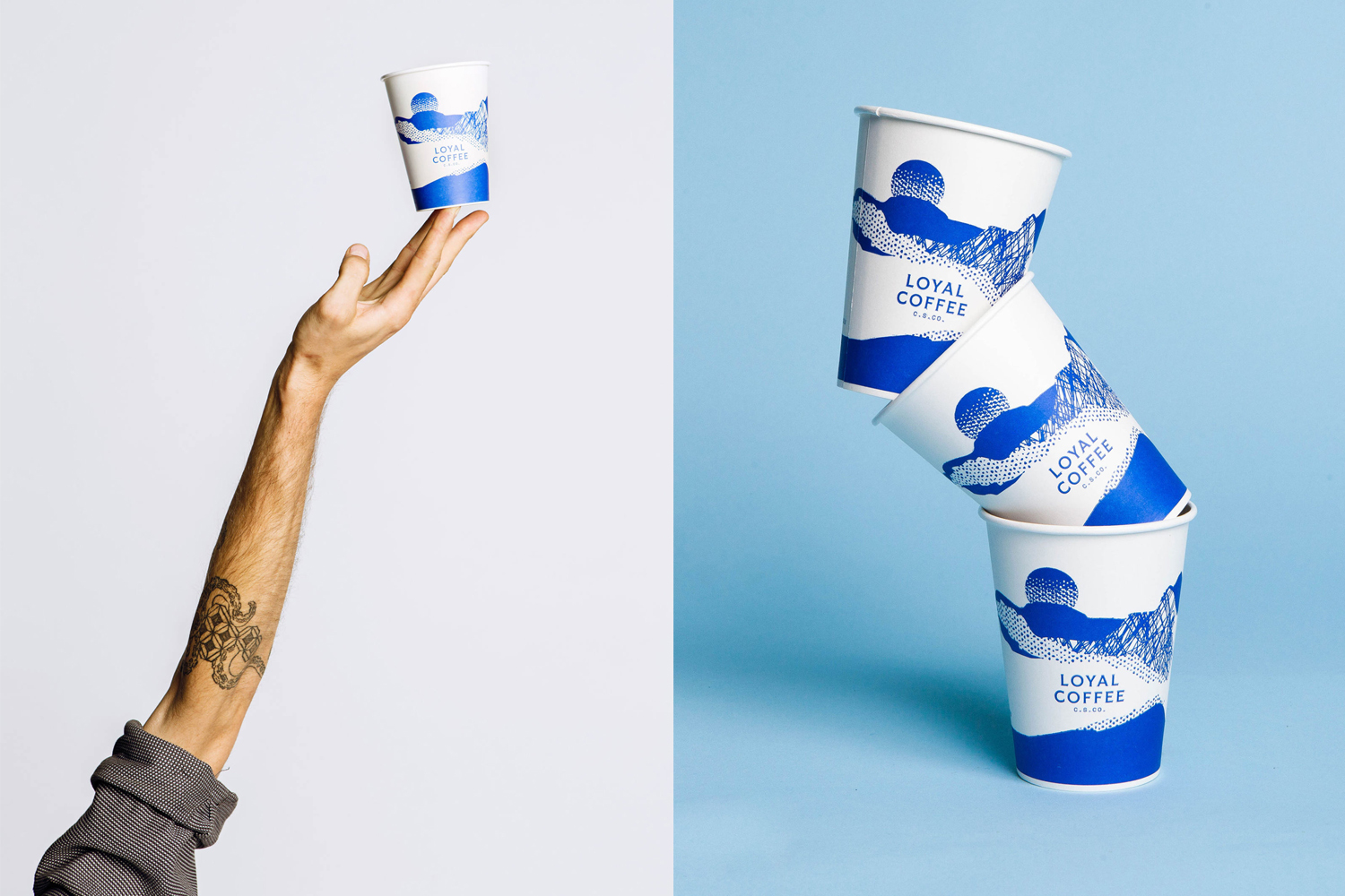 A hand balancing a blue and white branded coffee cup against a seamless white background, alongside a stacked arrangement of paper cups.
