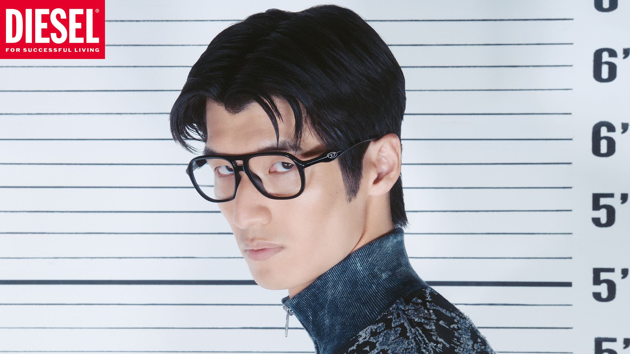Man wearing black eyeglasses and patterned high-neck top against a police height chart wall for Diesel campaign