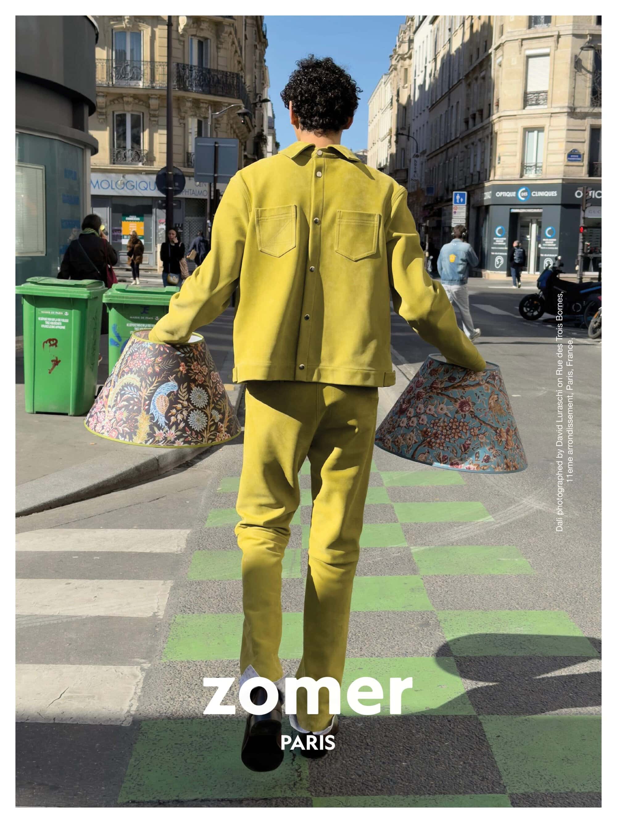Model from behind walking down a city street wearing a chartreuse yellow matching set while holding patterned lampshades.
