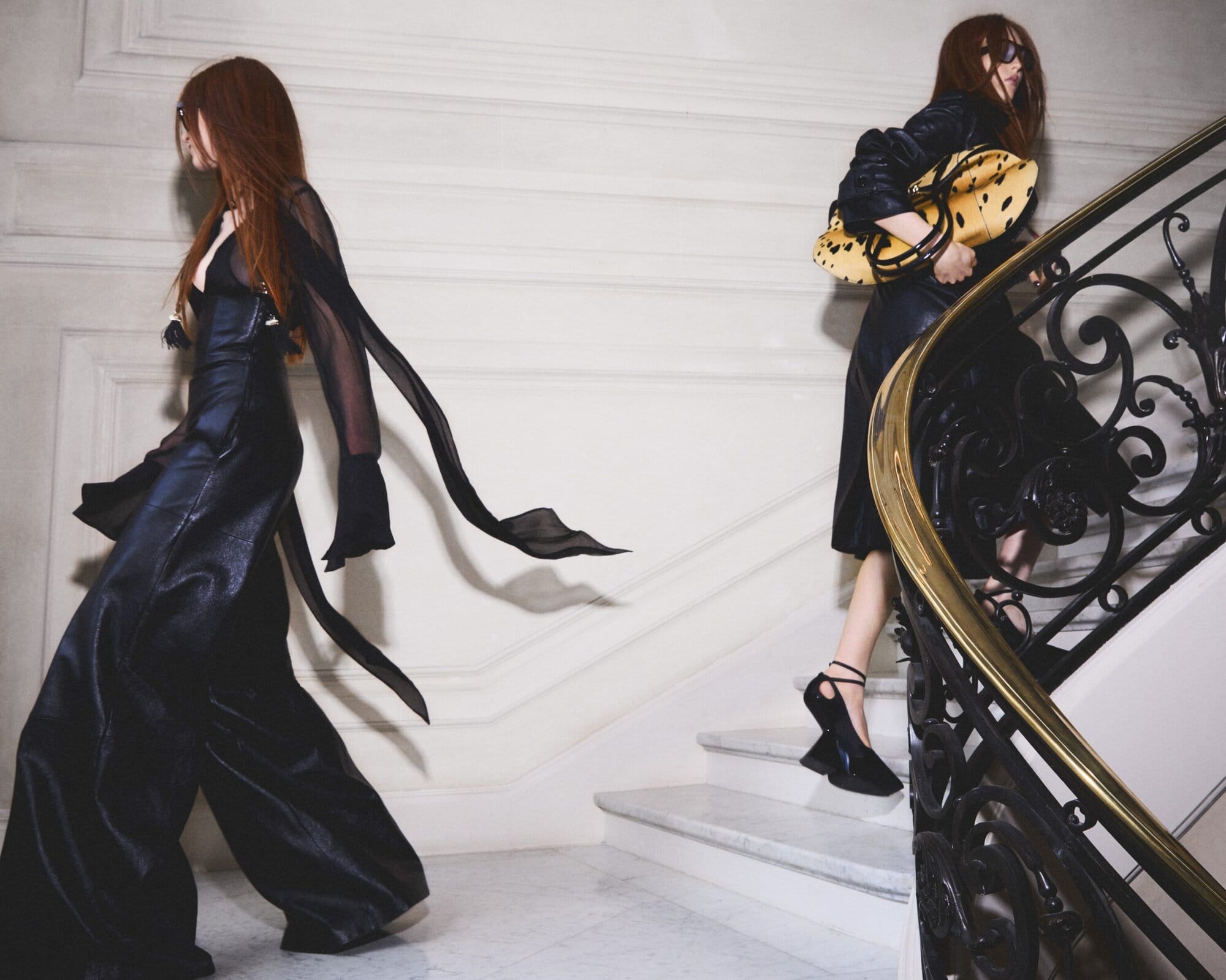 Two women in black outfits walking up an ornate staircase with a gilded handrail for Nina Ricci Fall 2025 campaign.