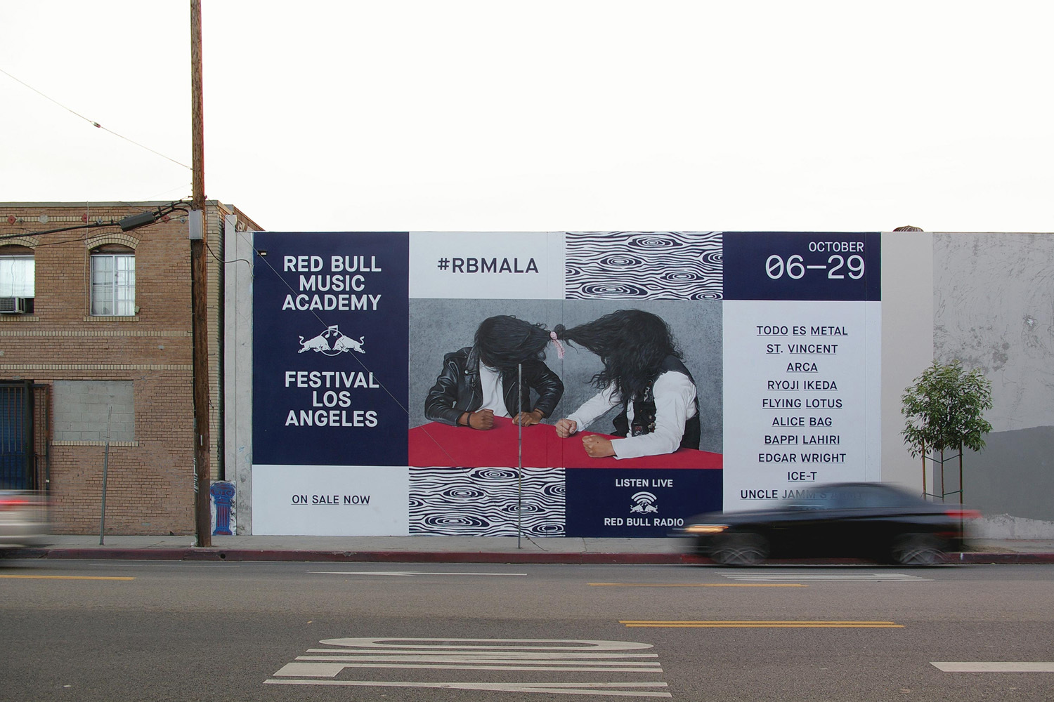 Large Red Bull Music Academy outdoor festival billboard on a city wall with typography and graphic panels above a street.