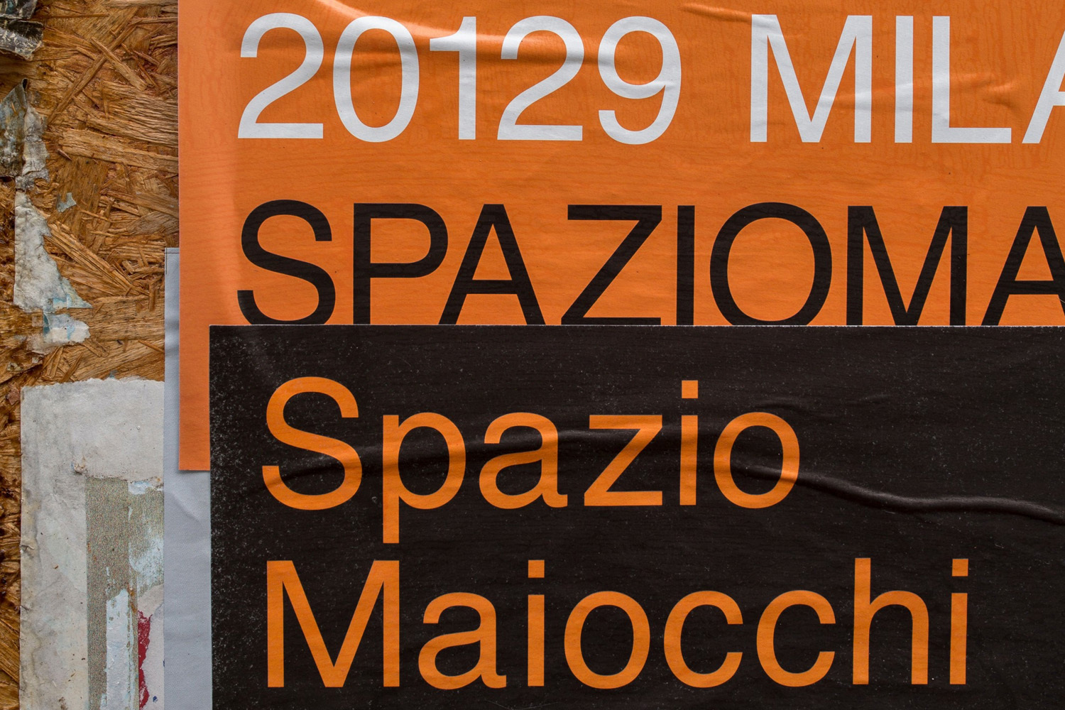 Layered typography posters with orange and black panels displaying Italian text on a textured wooden background.