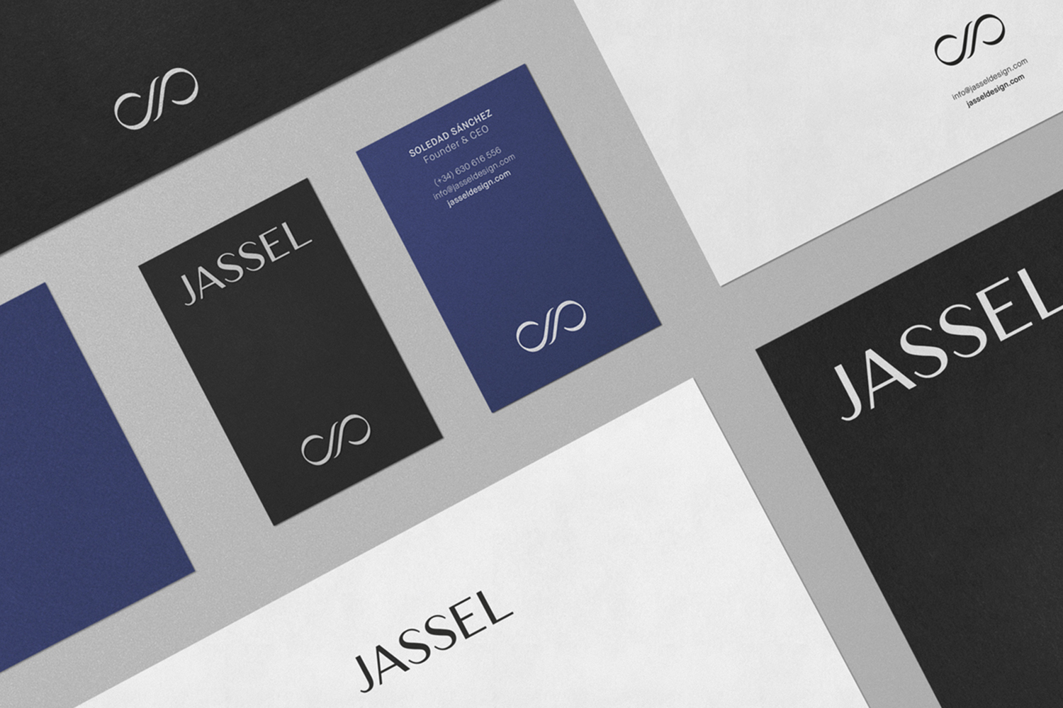Flat lay of corporate stationery for Jassel featuring black, white, and blue business cards and letterhead on a grey surface