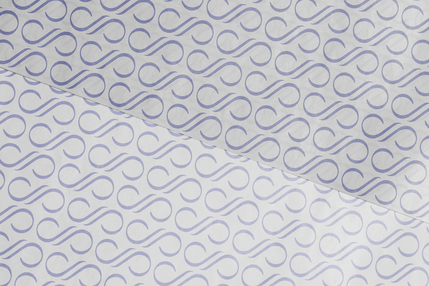 Close-up of patterned white tissue paper featuring a repeating purple monogram motif arranged in diagonal rows.
