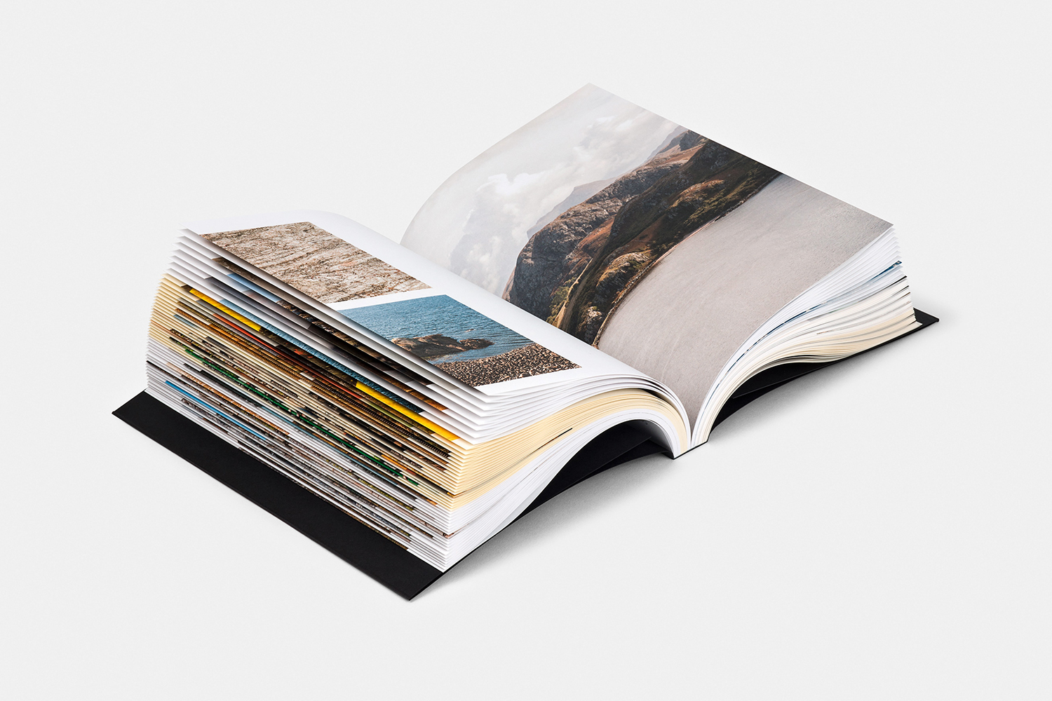 An open hardcover book displaying colorful pages and photographic prints against a solid white background.