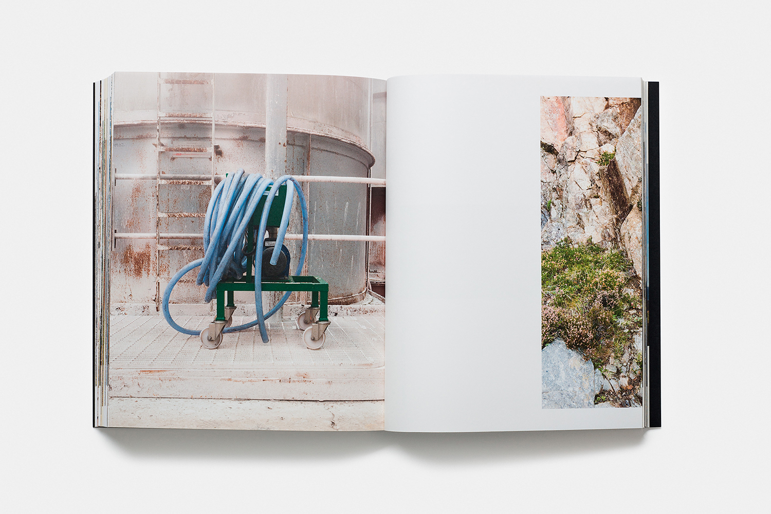 Open book displaying industrial photography on the left page and a rocky outcrop on the right page against a white background