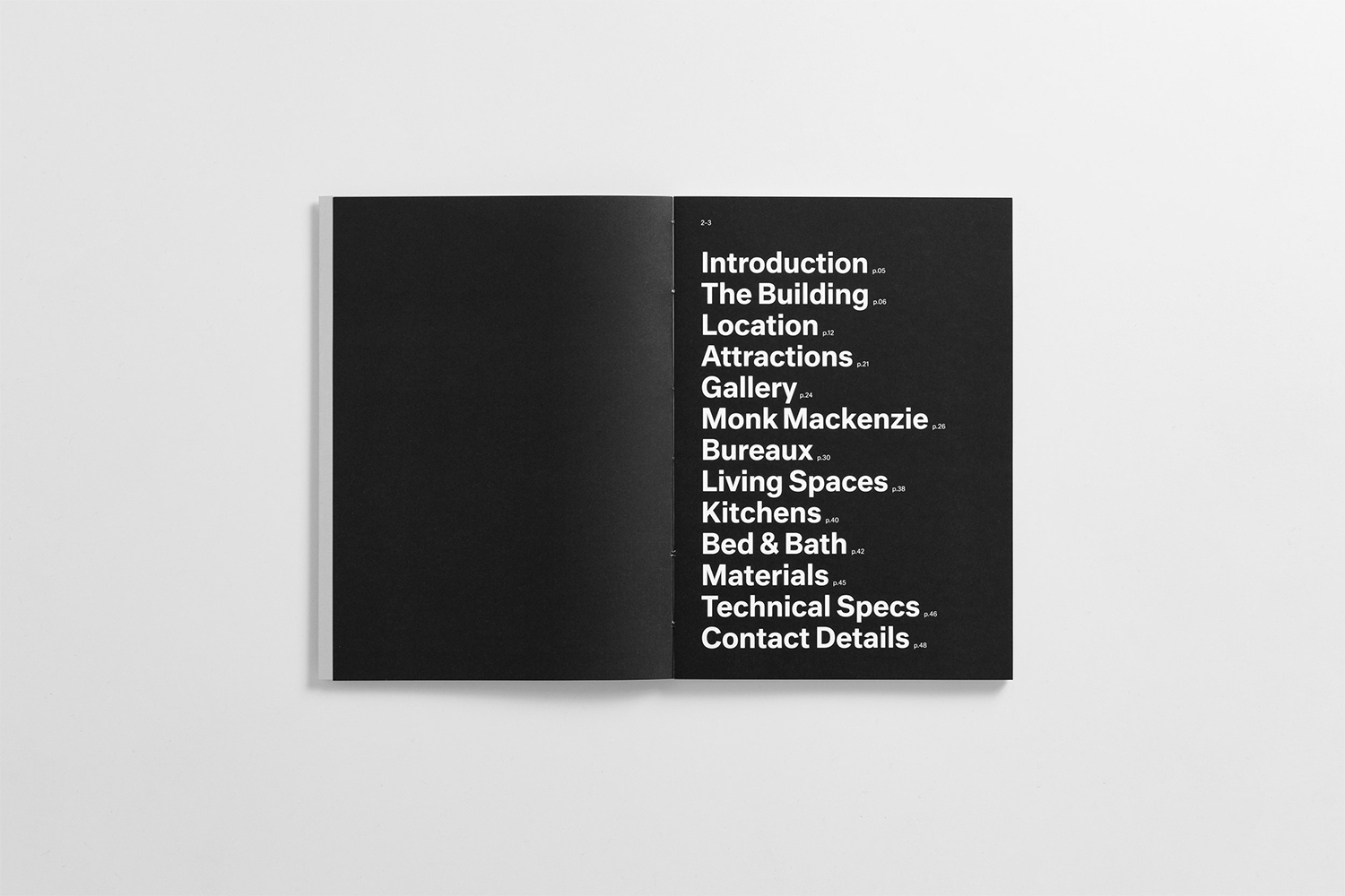 Open brochure spread showing white sans-serif typography on a black page against a neutral background