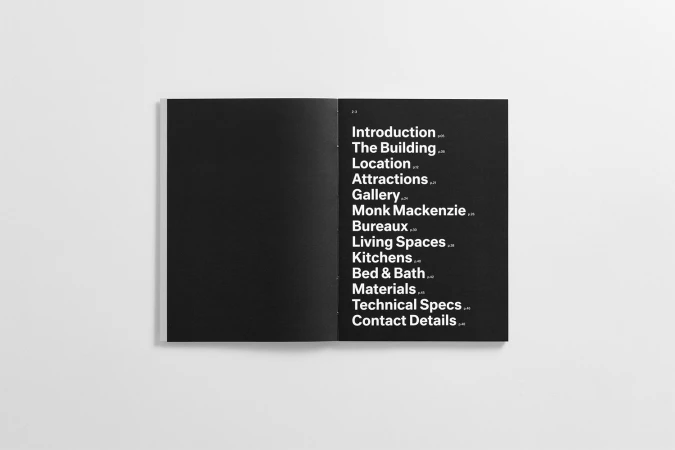 Open brochure spread showing white sans-serif typography on a black page against a neutral background