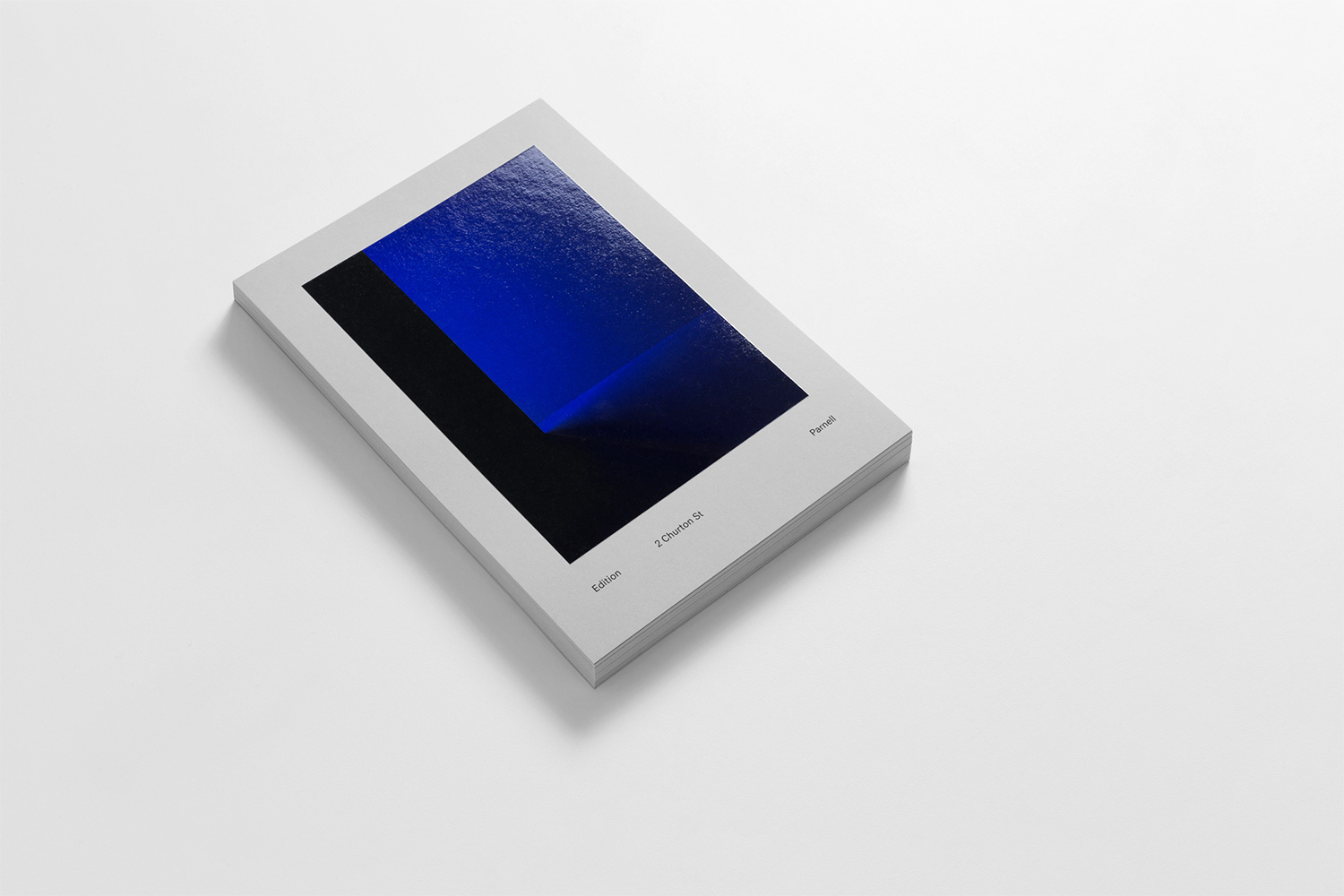 A stack of minimalist white brochures featuring a deep blue and black abstract cover design resting on a clean white surface.