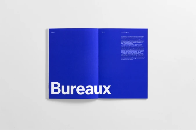 Open magazine spread on white surface featuring solid blue page with bold white typography reading Bureaux.
