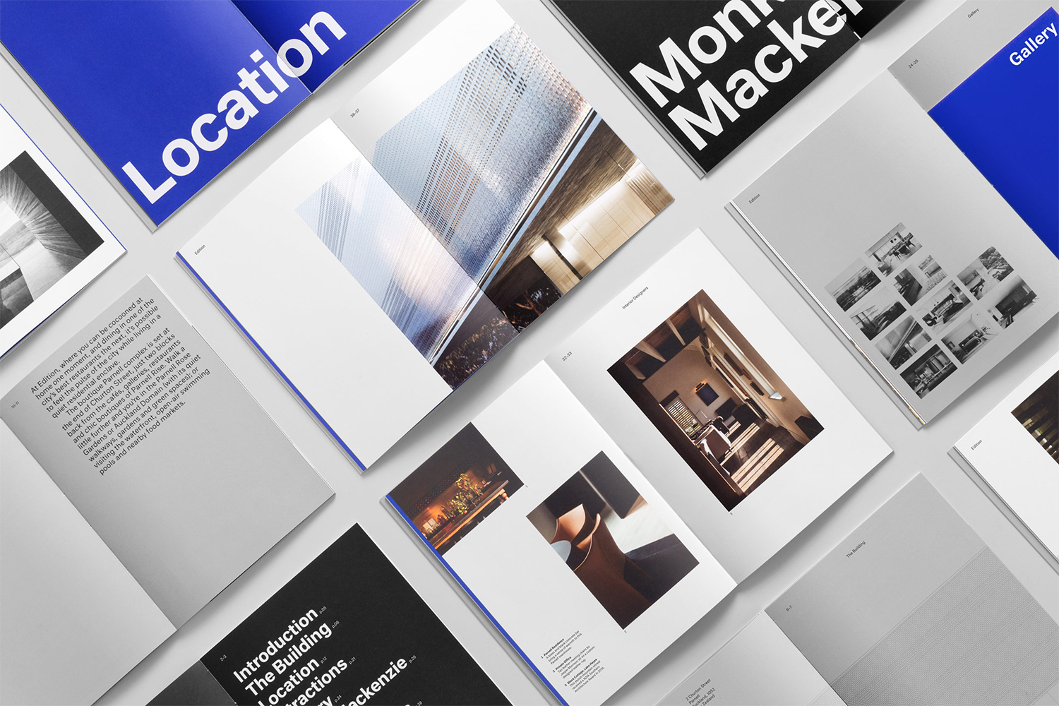Flat lay photograph showing multiple open brand identity brochures and editorial spreads with minimalist typography and architectural photography.