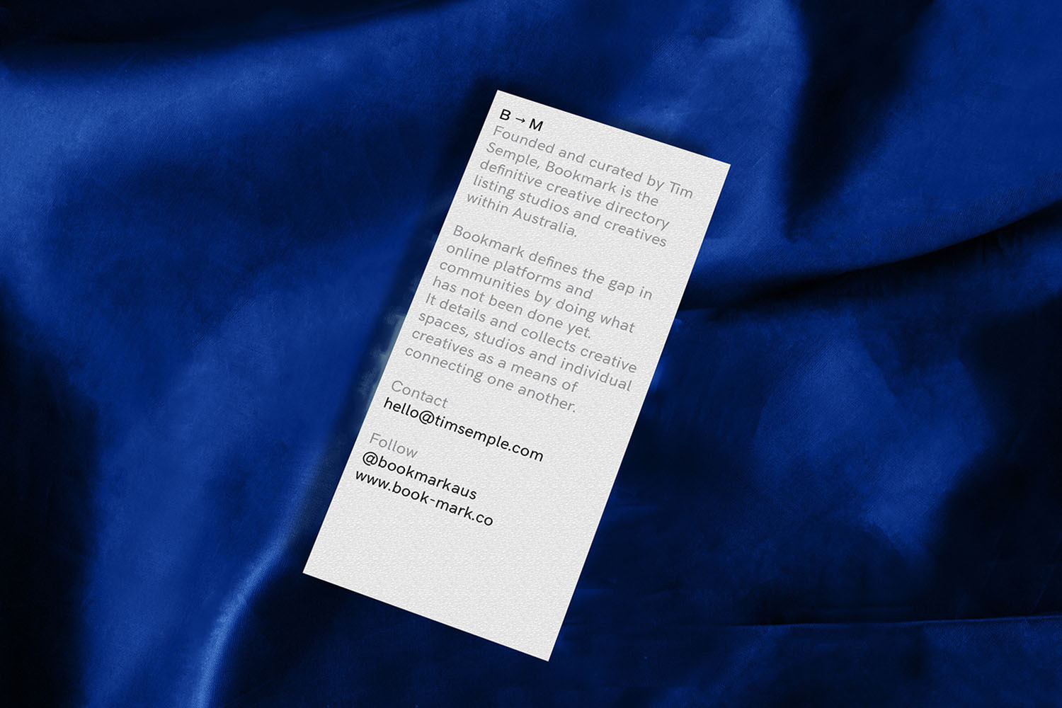 White promotional card with dark text resting on a textured royal blue fabric background.