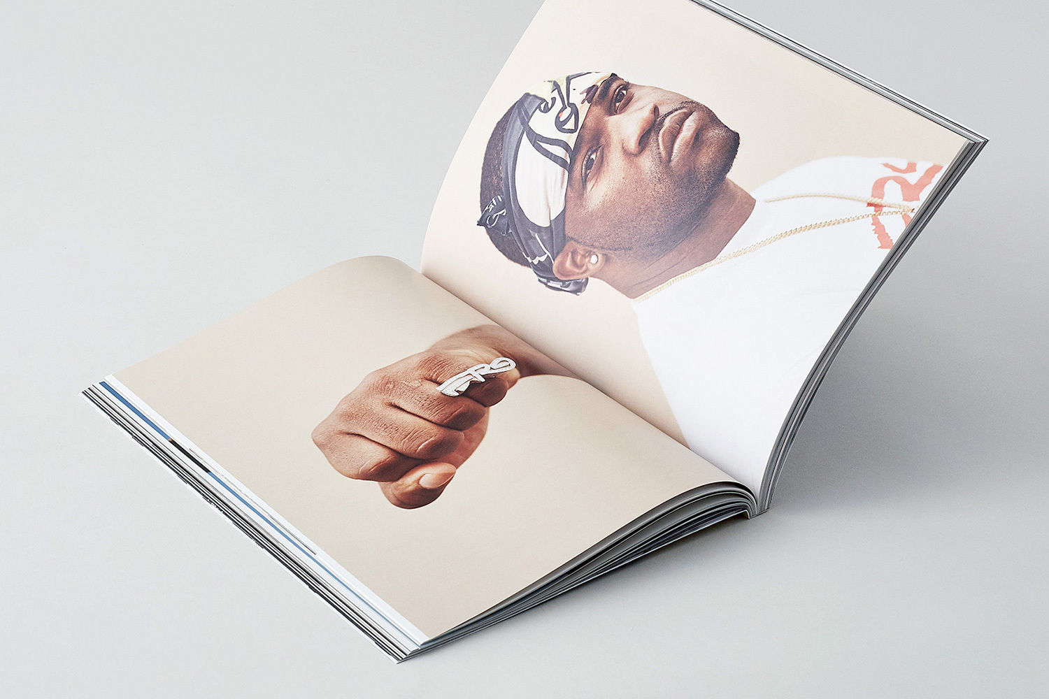 An open magazine spread displaying a portrait of a man wearing a patterned head wrap and a ring on his clenched fist