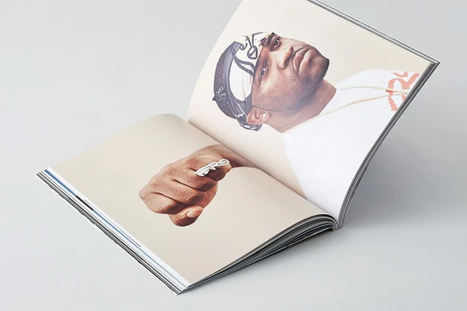 An open magazine spread displaying a portrait of a man wearing a patterned head wrap and a ring on his clenched fist