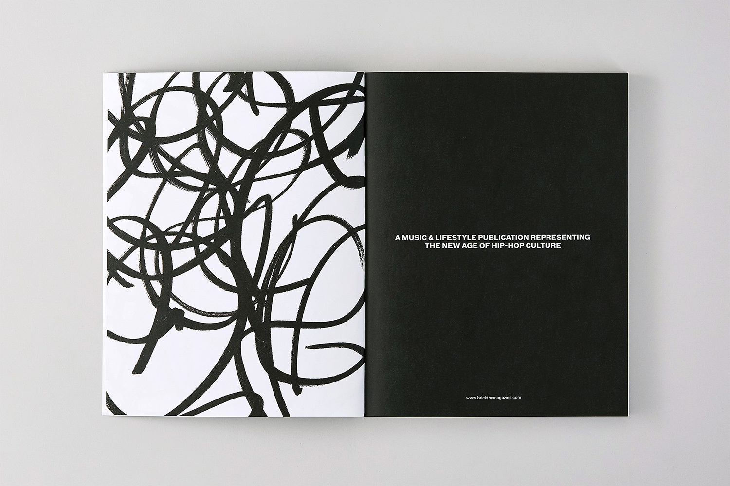 Open magazine spread showing abstract black brush strokes on the left and white text on a solid black page on the right