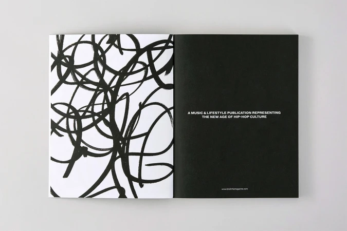 Open magazine spread showing abstract black brush strokes on the left and white text on a solid black page on the right