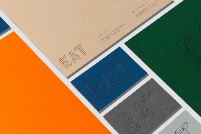 Flat lay of Eat Furniture brand stationery including letterhead and business cards in blue, green, and neutral tones.