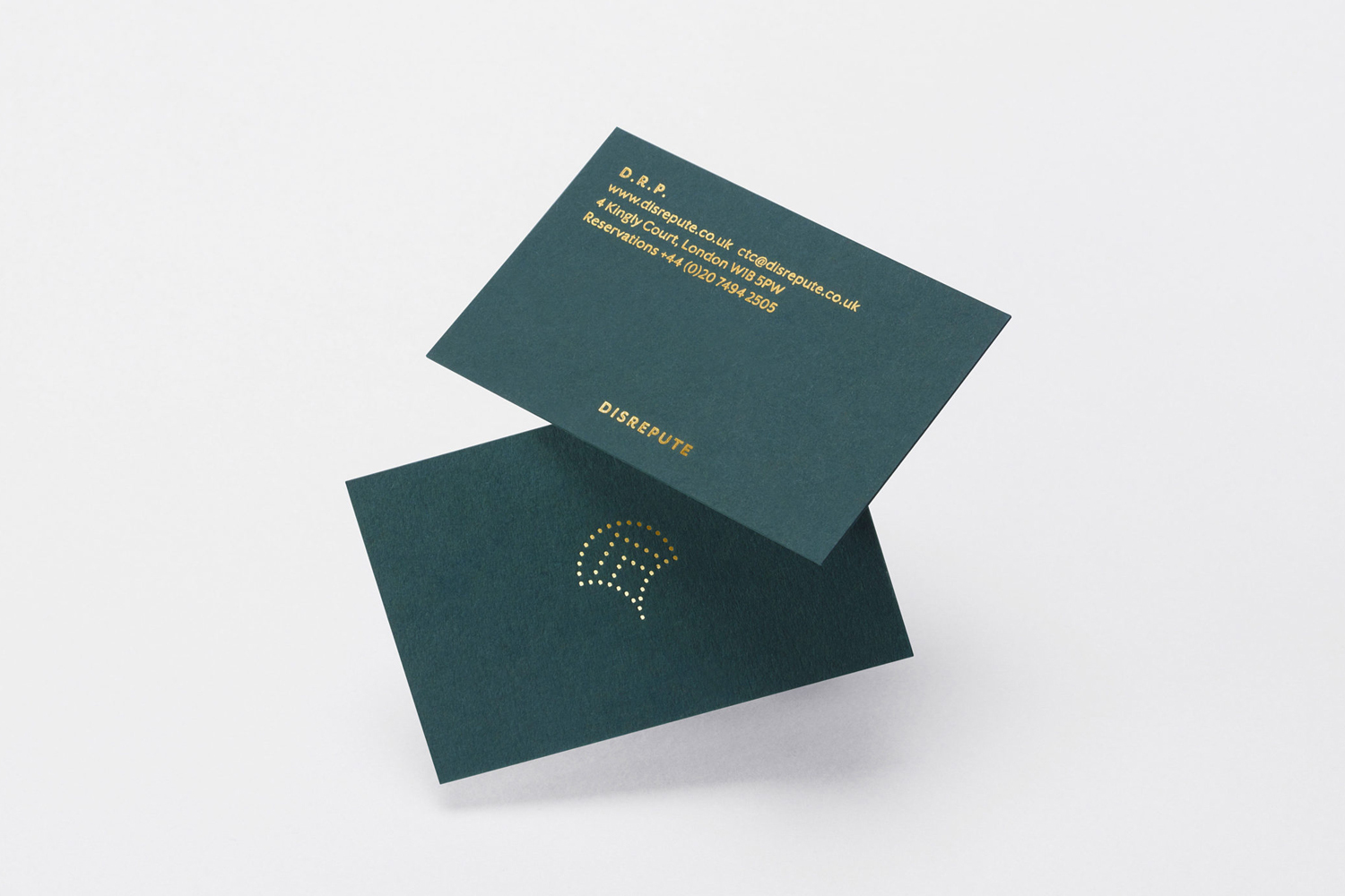 Two dark green business cards with gold foil lettering and logo displayed against a plain white background