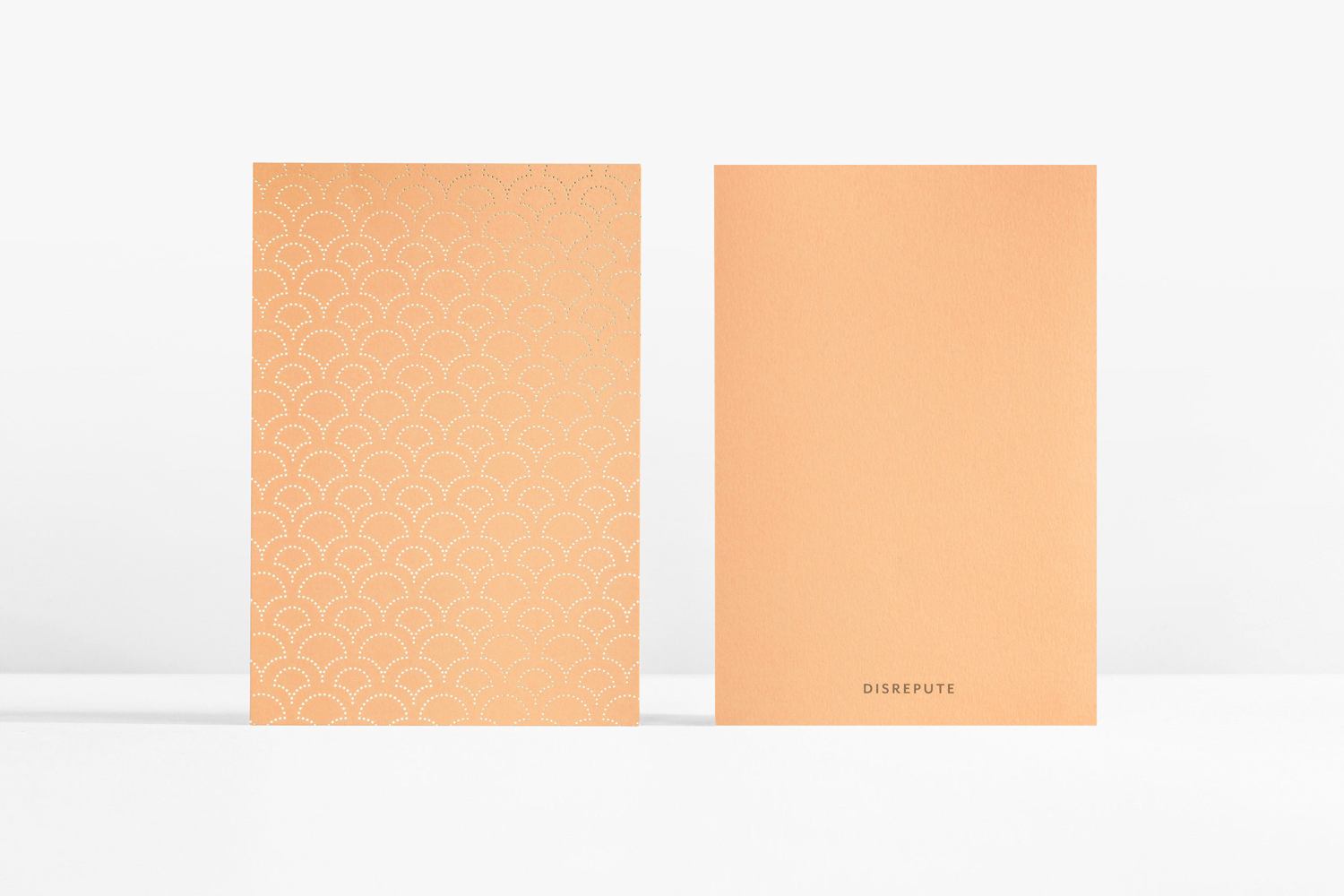 Two peach-coloured cards displayed against a white seamless background with typographic branding
