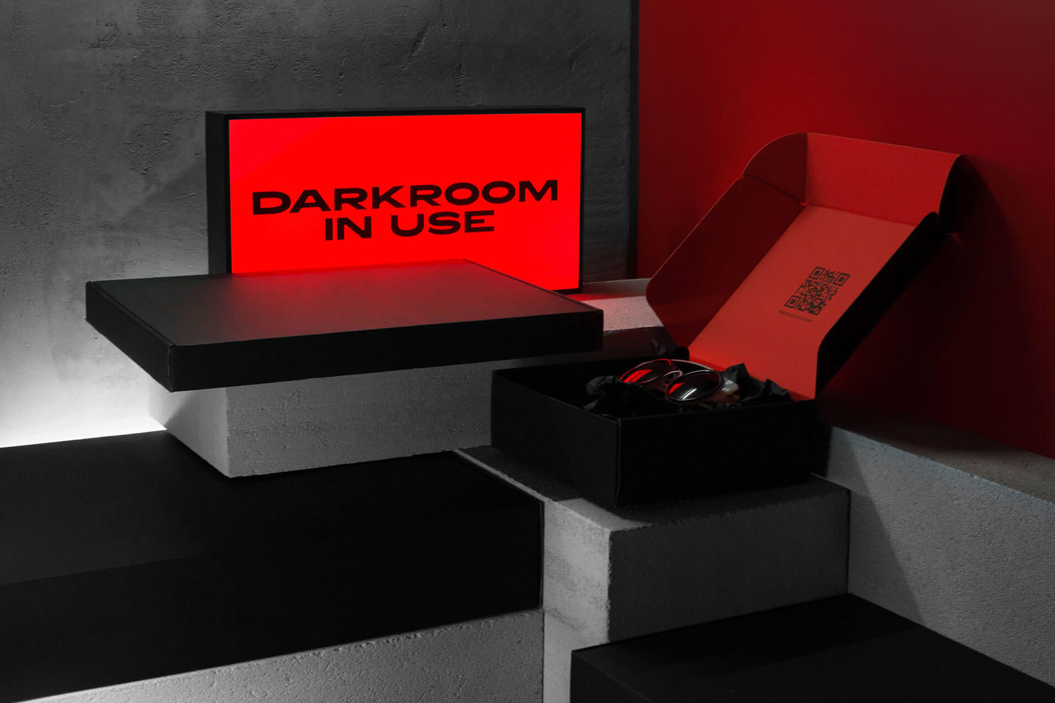 Black and red branded packaging boxes displayed on concrete steps with a glowing sign