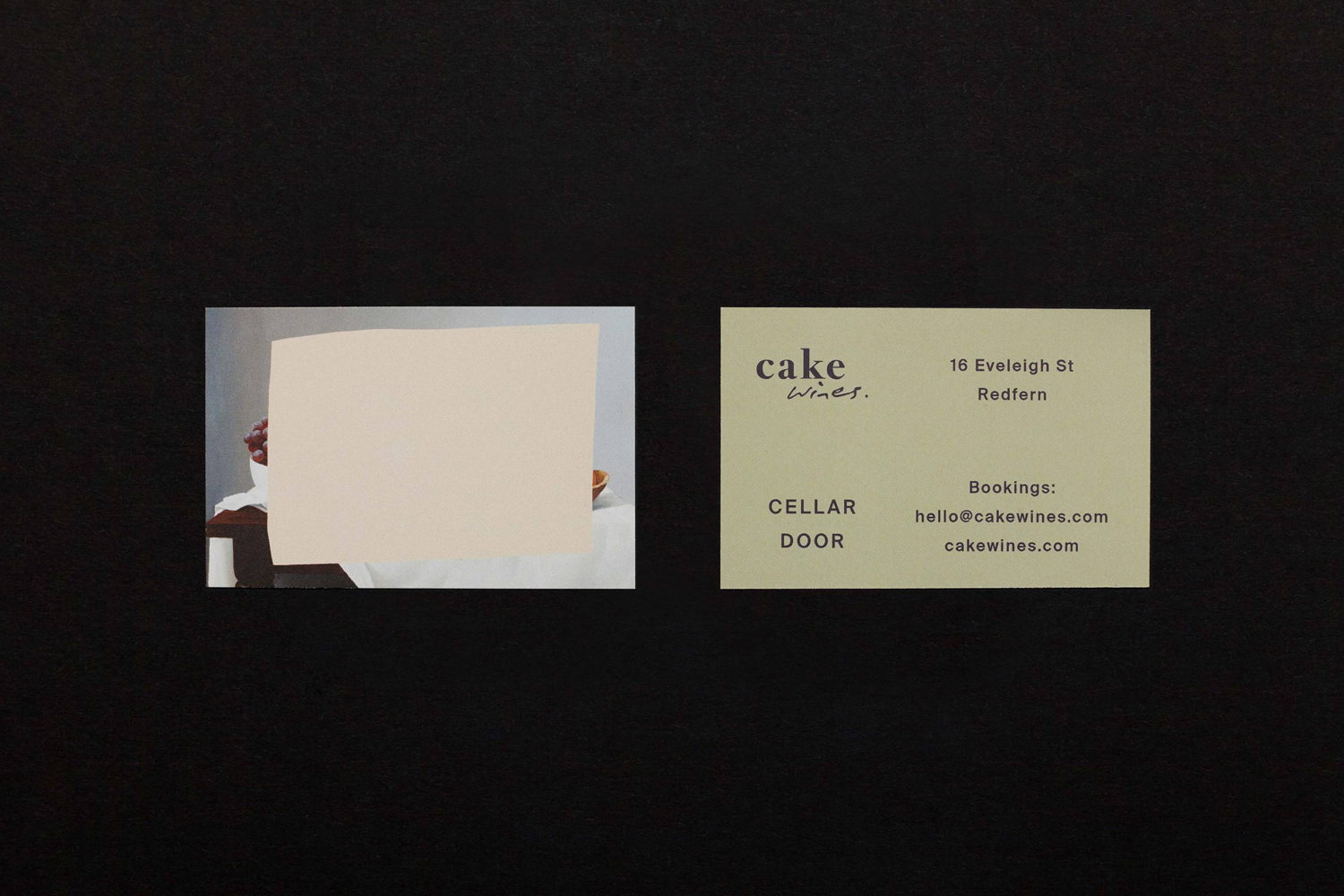 Two business cards for Cake Wines featuring minimalist graphic design set against a dark textured surface