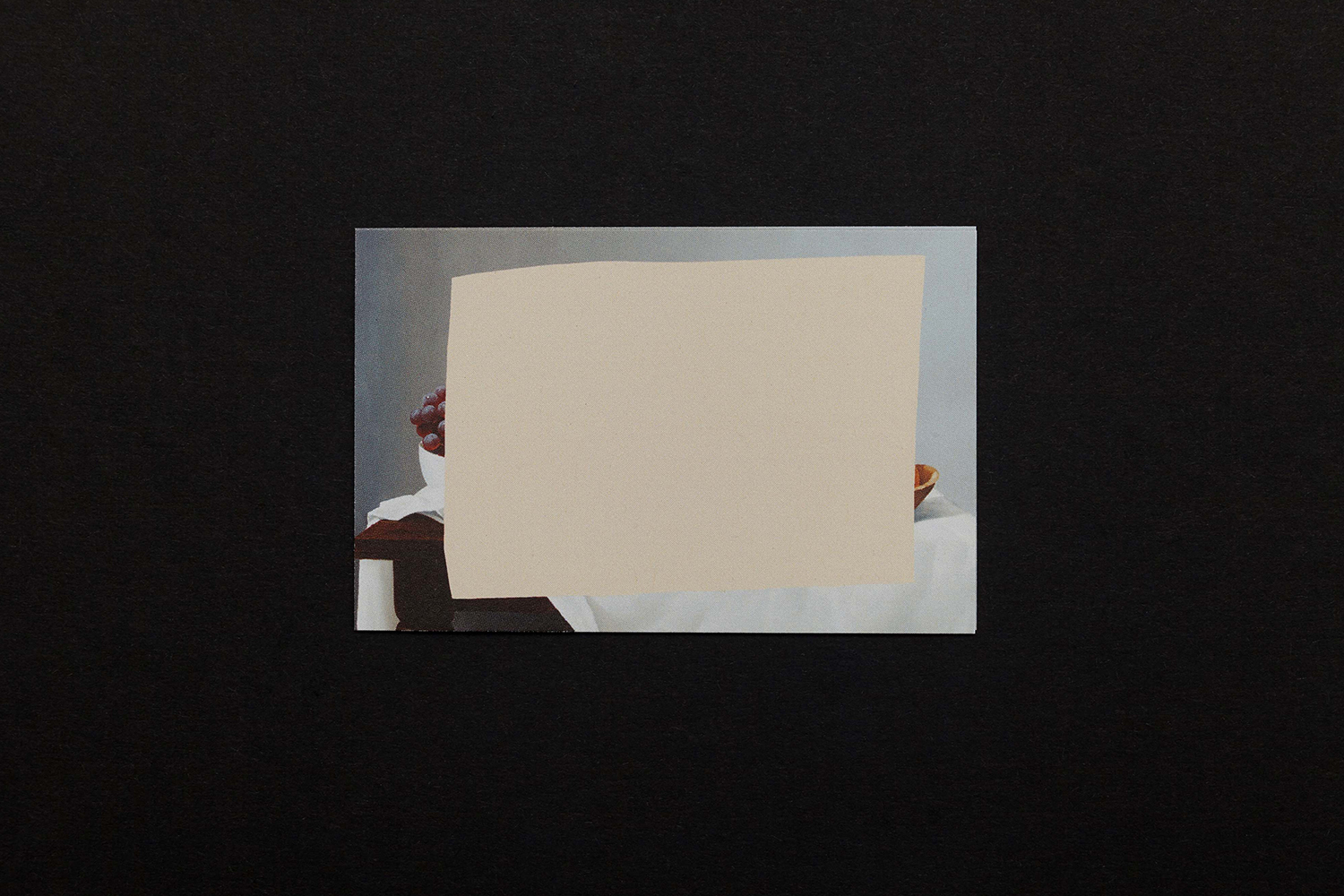 Still life painting print partially covered by a beige paper cutout, set against a black background.