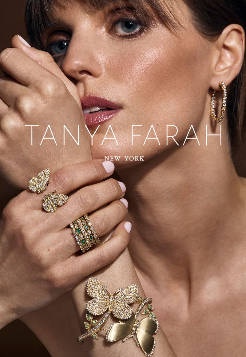 Close-up of a woman with fair skin wearing butterfly-themed earrings, rings, and a bracelet in a jewelry ad for Tanya Farah New York.