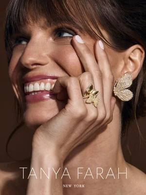 Close-up portrait of a smiling model wearing butterfly-shaped diamond ring and matching earrings for Tanya Farah New York